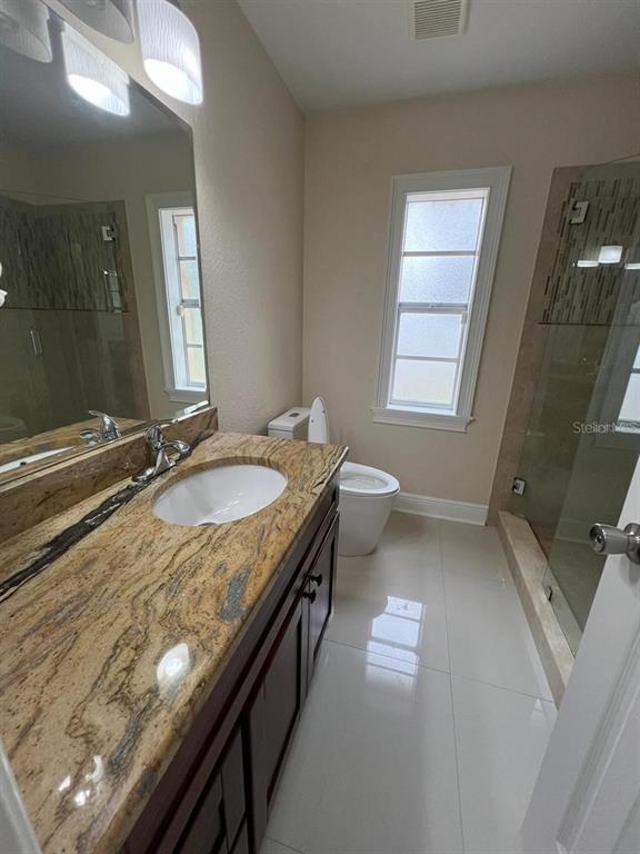5602 Joyner Road Tampa, FL 33624 - Photo 21 of 28 a bathroom with a granite countertop sink a toilet and a mirror