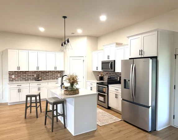 a kitchen with kitchen island a refrigerator a stove a dining table and chairs with wooden floor