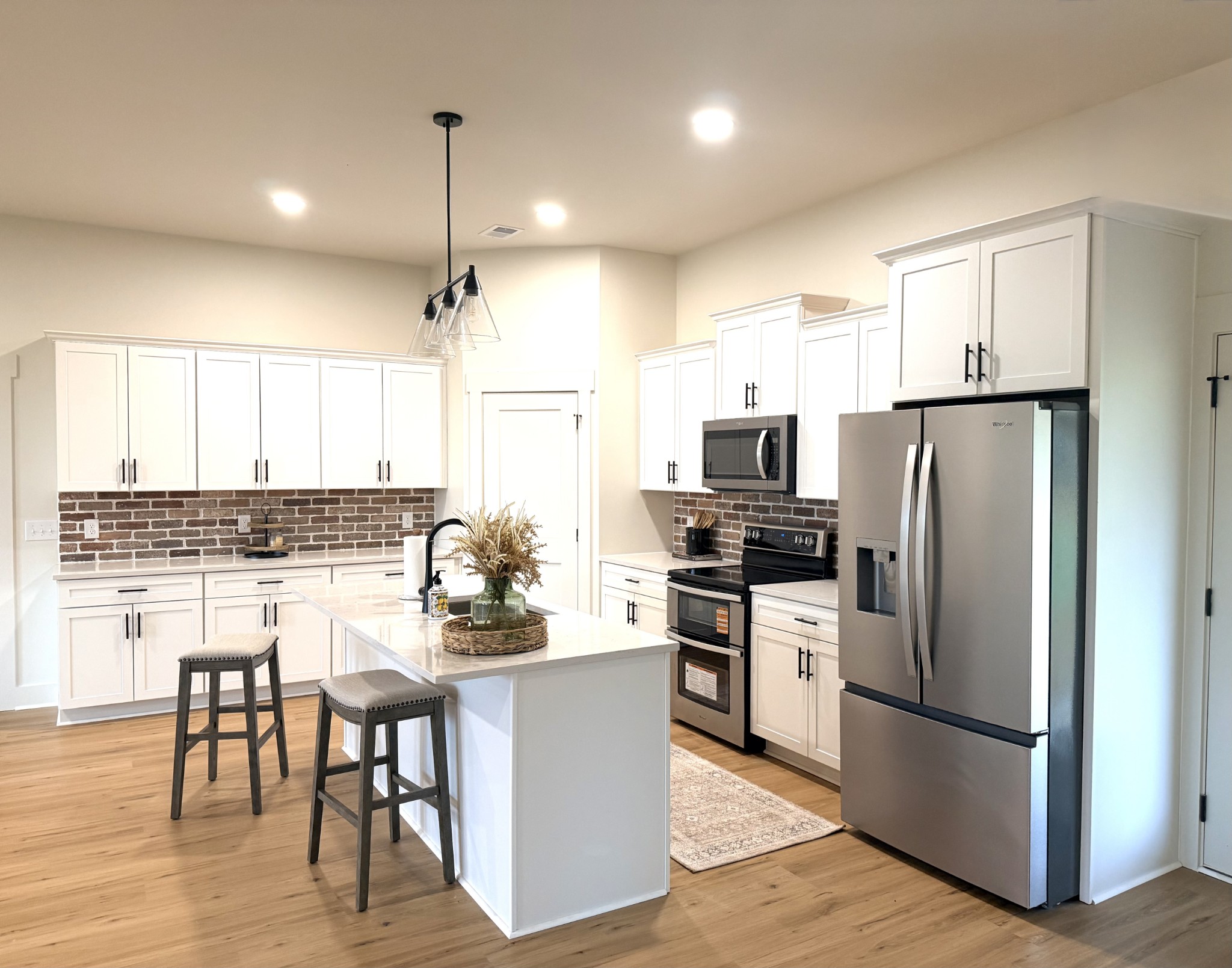4031 Wells Road Springfield, TN 37172 - Photo 8 of 23 a kitchen with kitchen island a refrigerator a stove a dining table and chairs with wooden floor