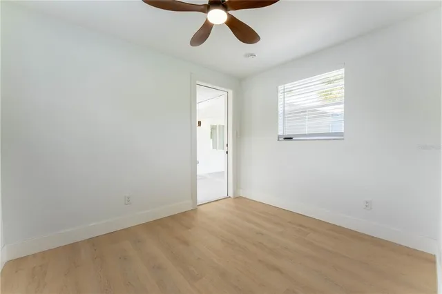 an empty room with a chandelier fan and windows