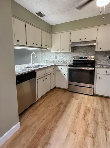 a kitchen with granite countertop white cabinets and appliances