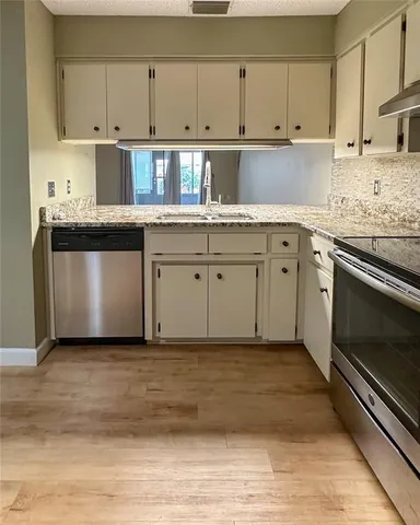 a kitchen with granite countertop cabinets stainless steel appliances and a sink