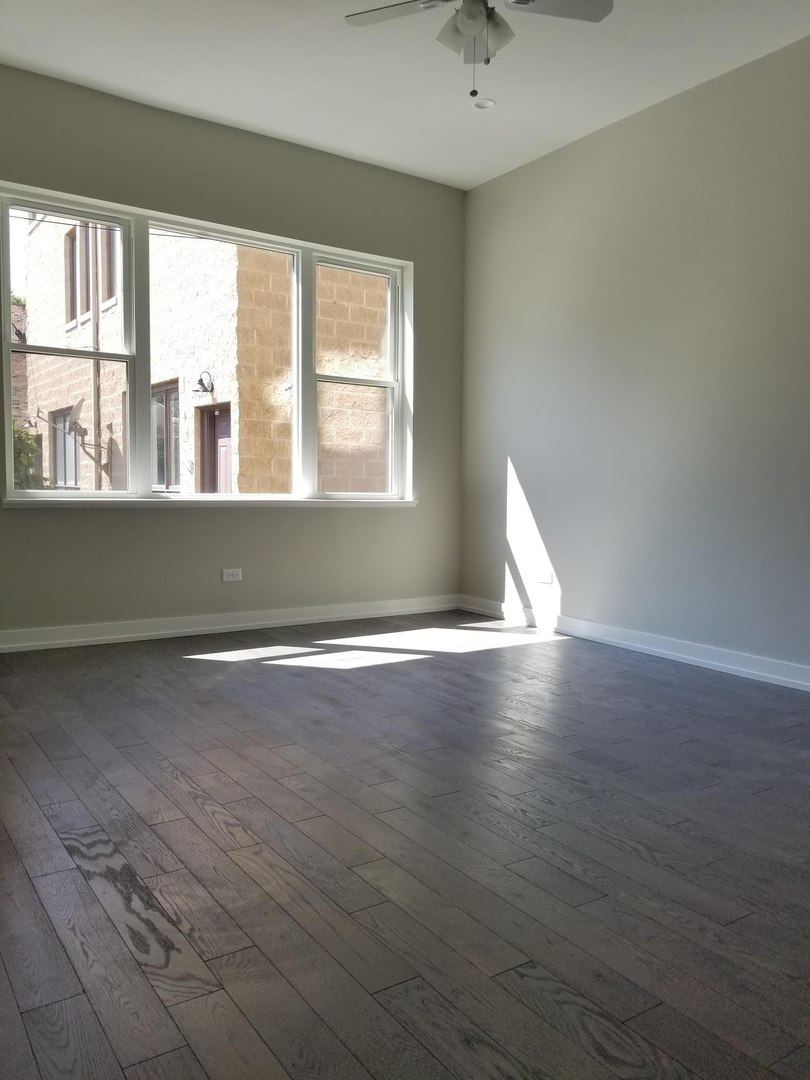 4764 North Virginia Avenue, Unit 112 Chicago, IL 60625 - Photo 6 of 12 an empty room with wooden floor and windows