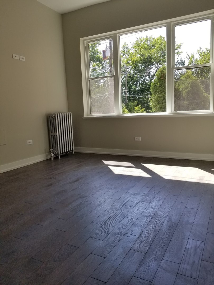 4764 North Virginia Avenue, Unit 112 Chicago, IL 60625 - Photo 7 of 12 an empty room with wooden floor and windows