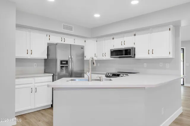 a kitchen with stainless steel appliances a refrigerator sink and white cabinets