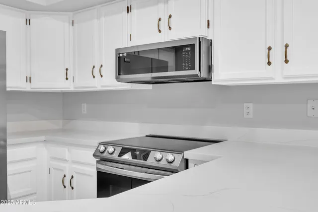 a kitchen with white cabinets and stainless steel appliances