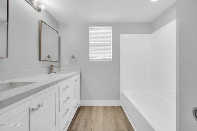 a spacious bathroom with a granite countertop sink a mirror and a bathtub