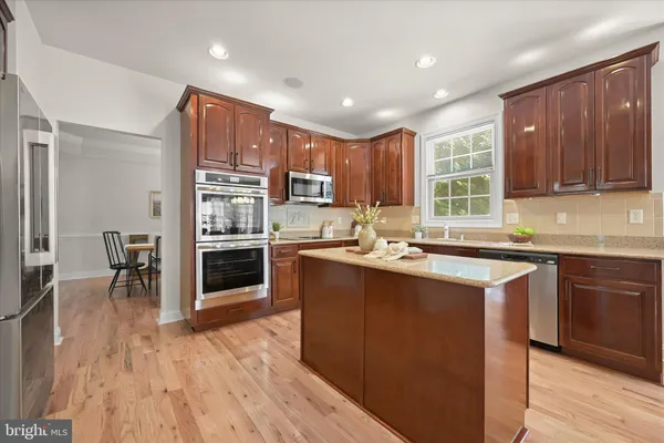 a kitchen with stainless steel appliances granite countertop a refrigerator a sink dishwasher a stove top oven a oven with wooden floors and cabinets