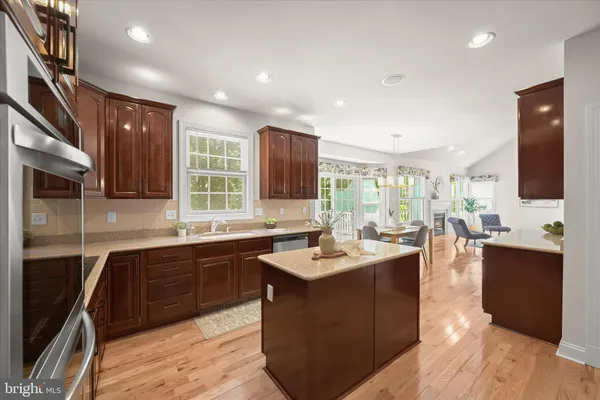 a large kitchen with stainless steel appliances a sink dishwasher a stove and black cabinets with wooden floor