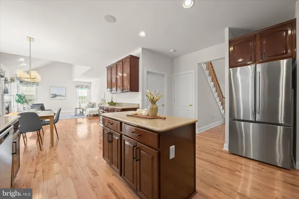 a kitchen with stainless steel appliances granite countertop a refrigerator a stove top oven a sink dishwasher and a refrigerator with wooden floor