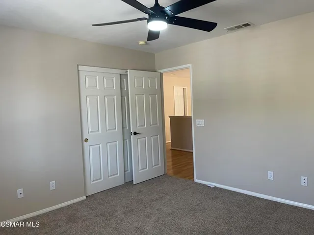 an empty room with closet and a ceiling fan