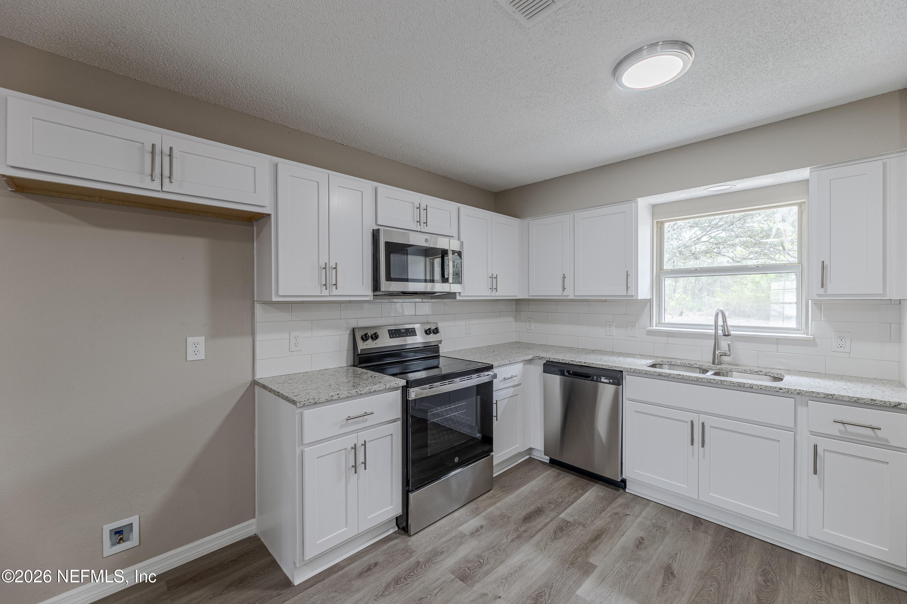 67104 Elnora Lane Yulee, FL 32097 - Photo 13 of 39 a kitchen with white cabinets stainless steel appliances and sink
