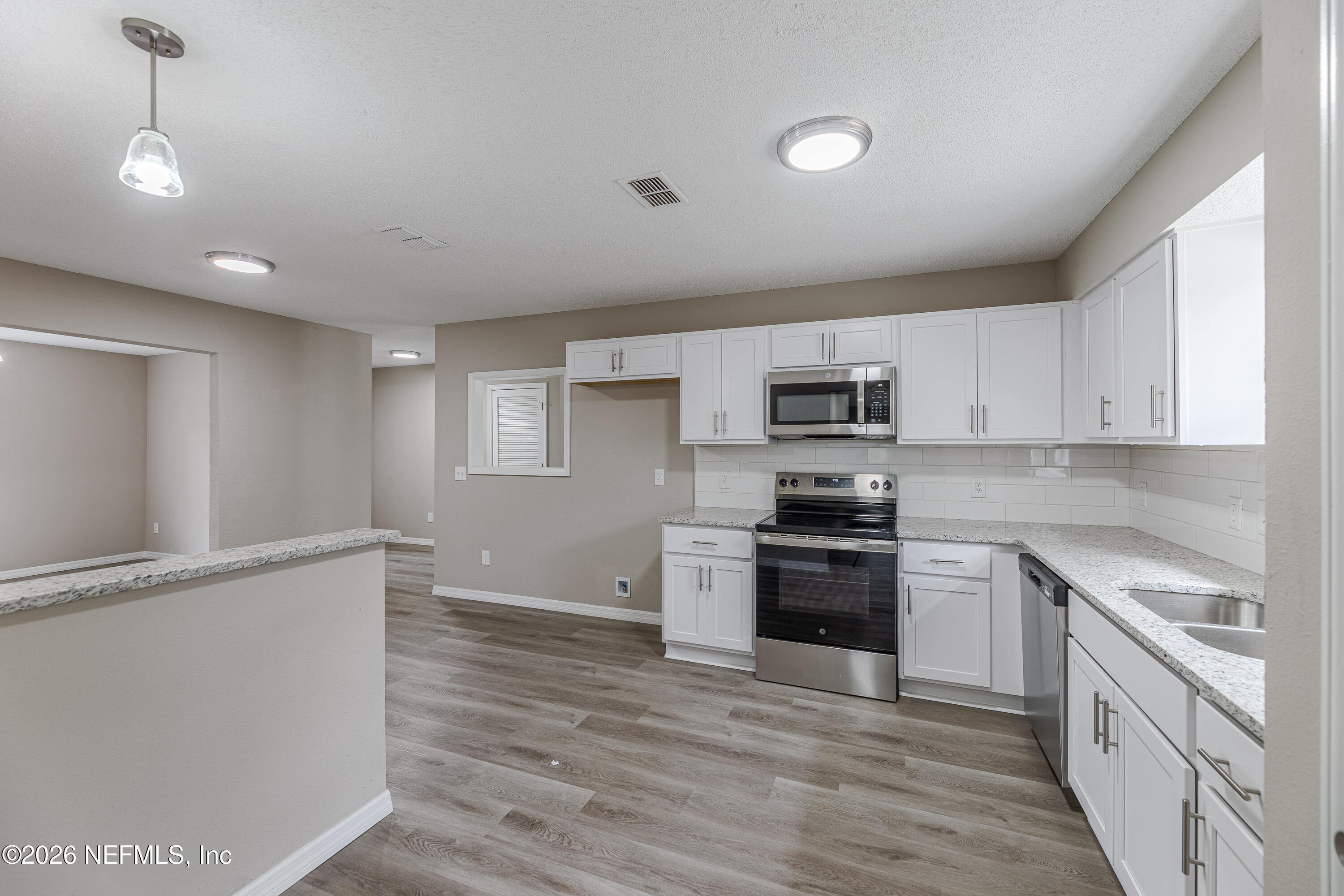 67104 Elnora Lane Yulee, FL 32097 - Photo 15 of 39 a kitchen with stainless steel appliances granite countertop a stove a sink and a refrigerator