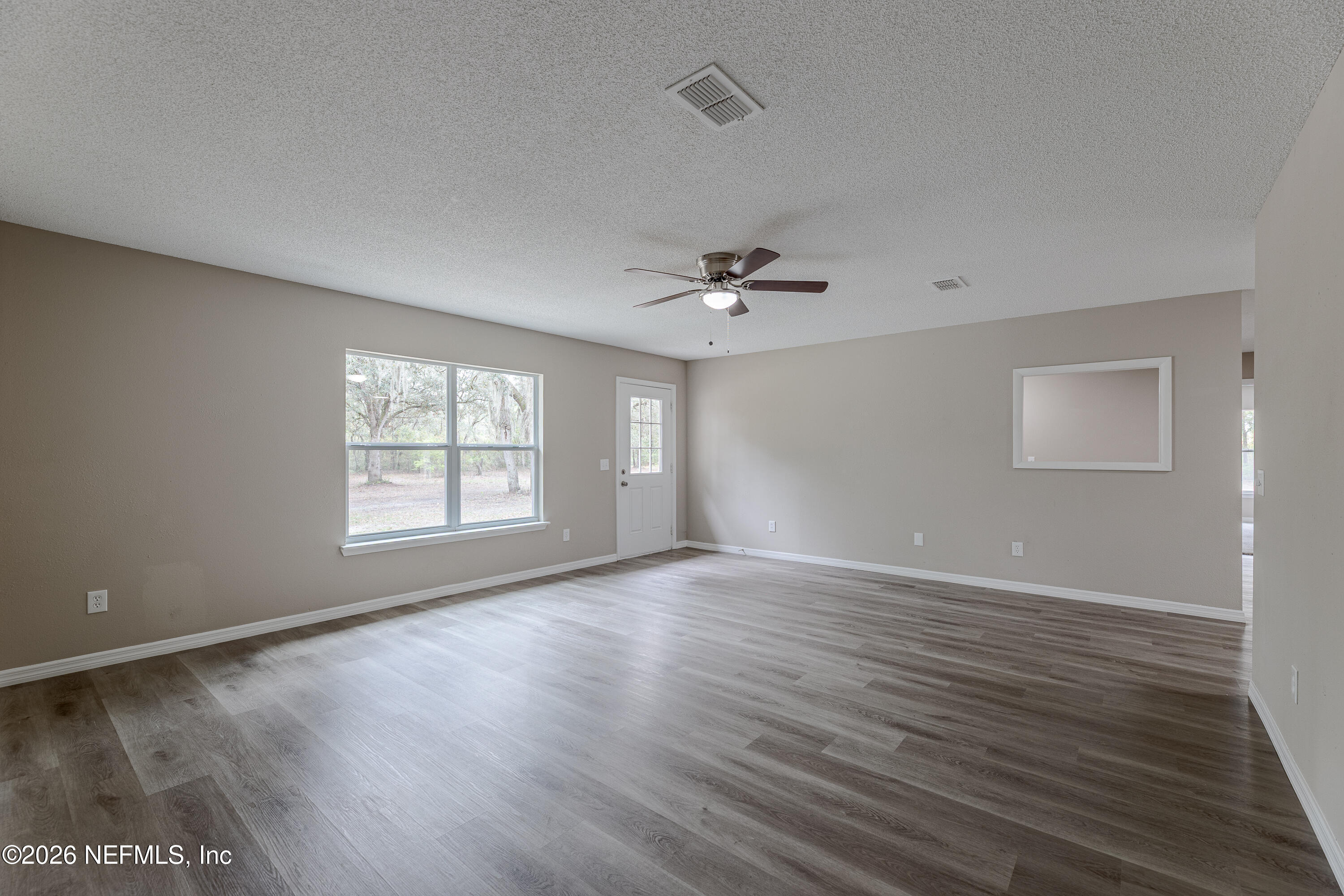 67104 Elnora Lane Yulee, FL 32097 - Photo 29 of 39 an empty room with wooden floor and windows
