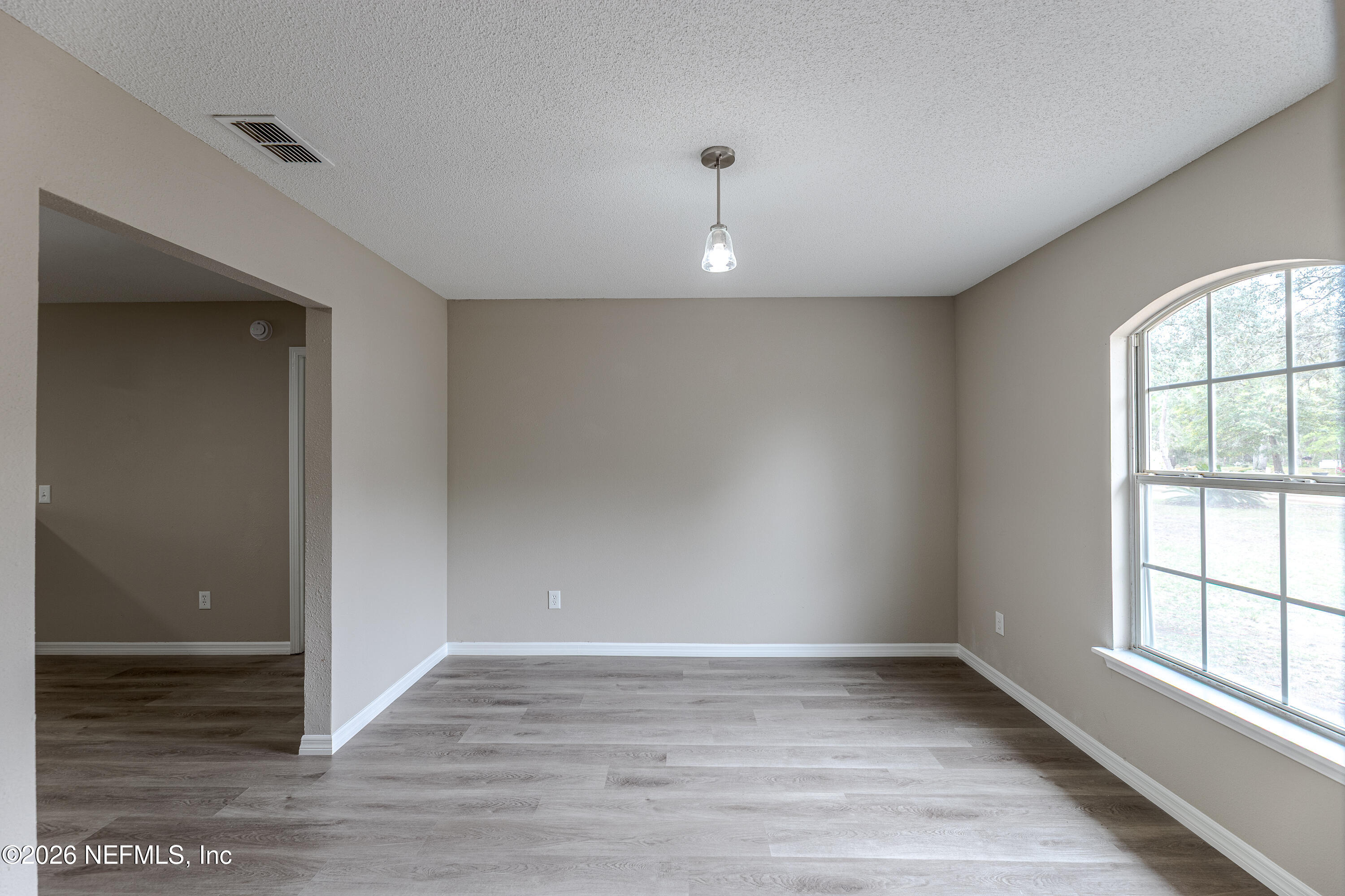 67104 Elnora Lane Yulee, FL 32097 - Photo 9 of 39 an empty room with wooden floor and windows