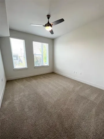 an empty room with windows and ceiling fan