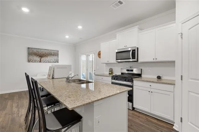 a kitchen with granite countertop white cabinets and stainless steel appliances
