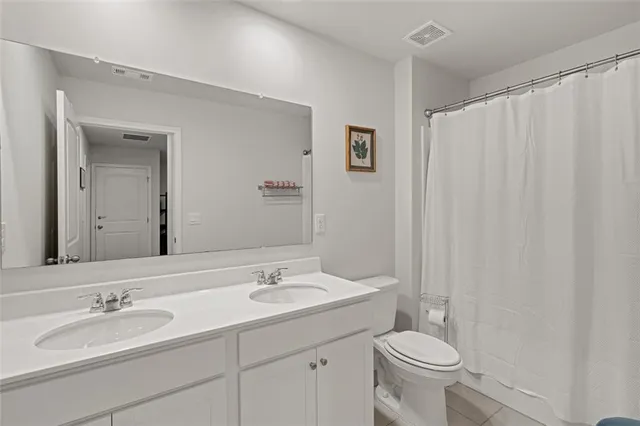 a bathroom with a double vanity sink toilet and a mirror