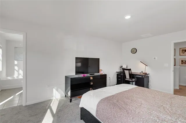 a bedroom with a bed and a flat tv screen on wall