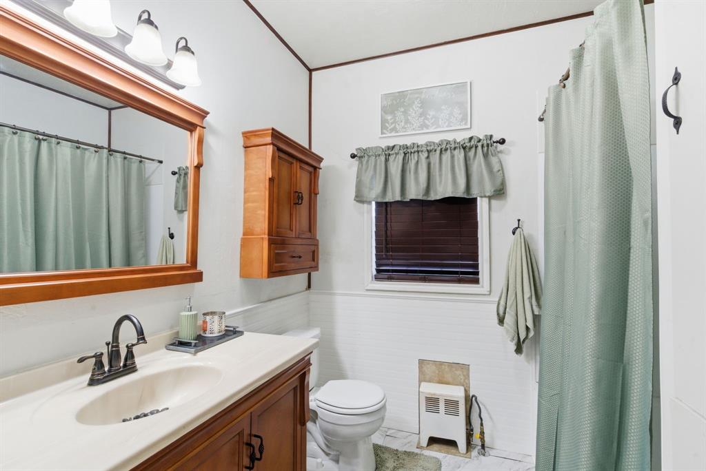 902 North Travis Street De Leon, TX 76444 - Photo 18 of 34 a bathroom with a sink a toilet and a mirror