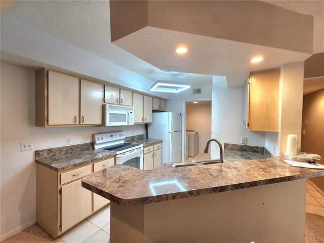a kitchen with granite countertop a sink a stove and cabinets