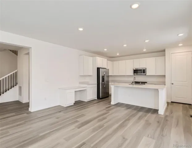 a kitchen with a refrigerator and white cabinets