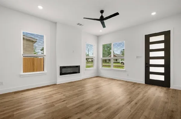 a view of an empty room with a window and wooden floor
