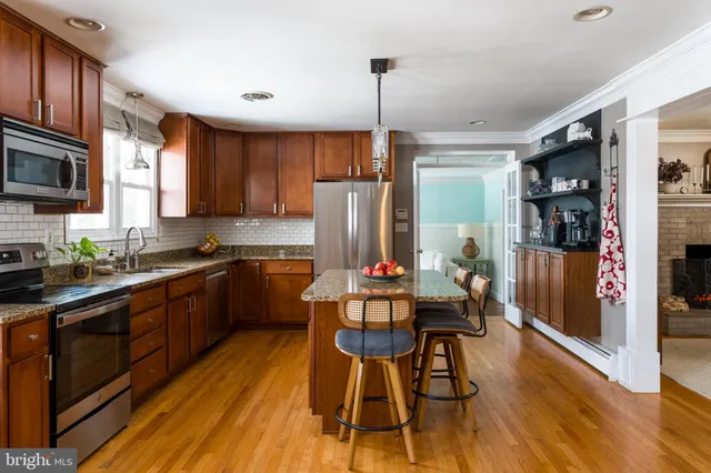 a kitchen with stainless steel appliances a dining table chairs a refrigerator and cabinets