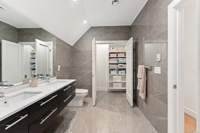 a spacious bathroom with a double vanity sink a toilet and a shower