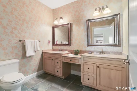a bathroom with a toilet a sink a mirror and vanity