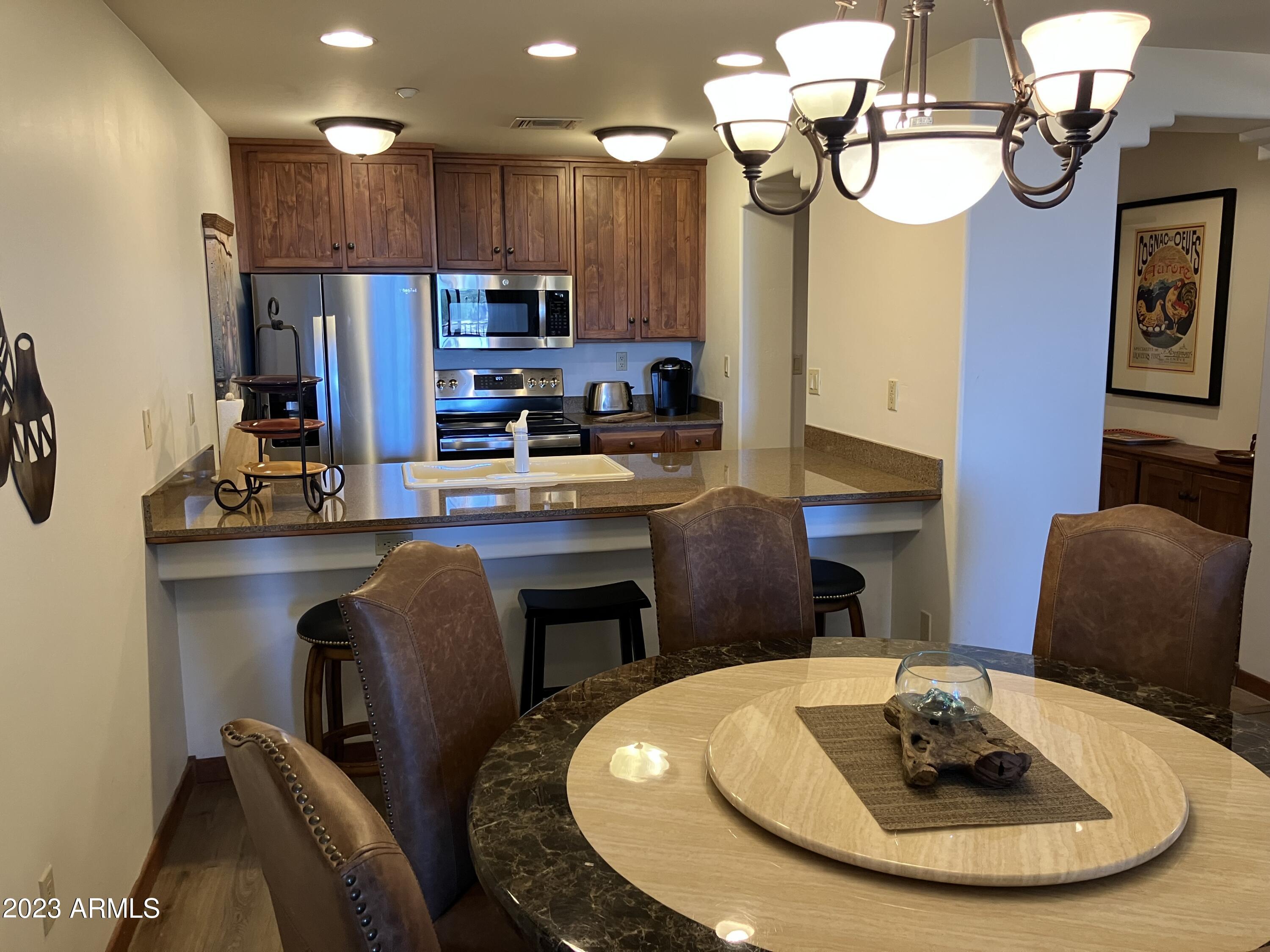 36601 North Mule Train Road, Unit 29C Carefree, AZ 85377 - Photo 4 of 35 a kitchen with stainless steel appliances granite countertop a sink a stove a dining table and chairs