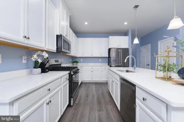a living room with stainless steel appliances furniture dining table and wooden floor