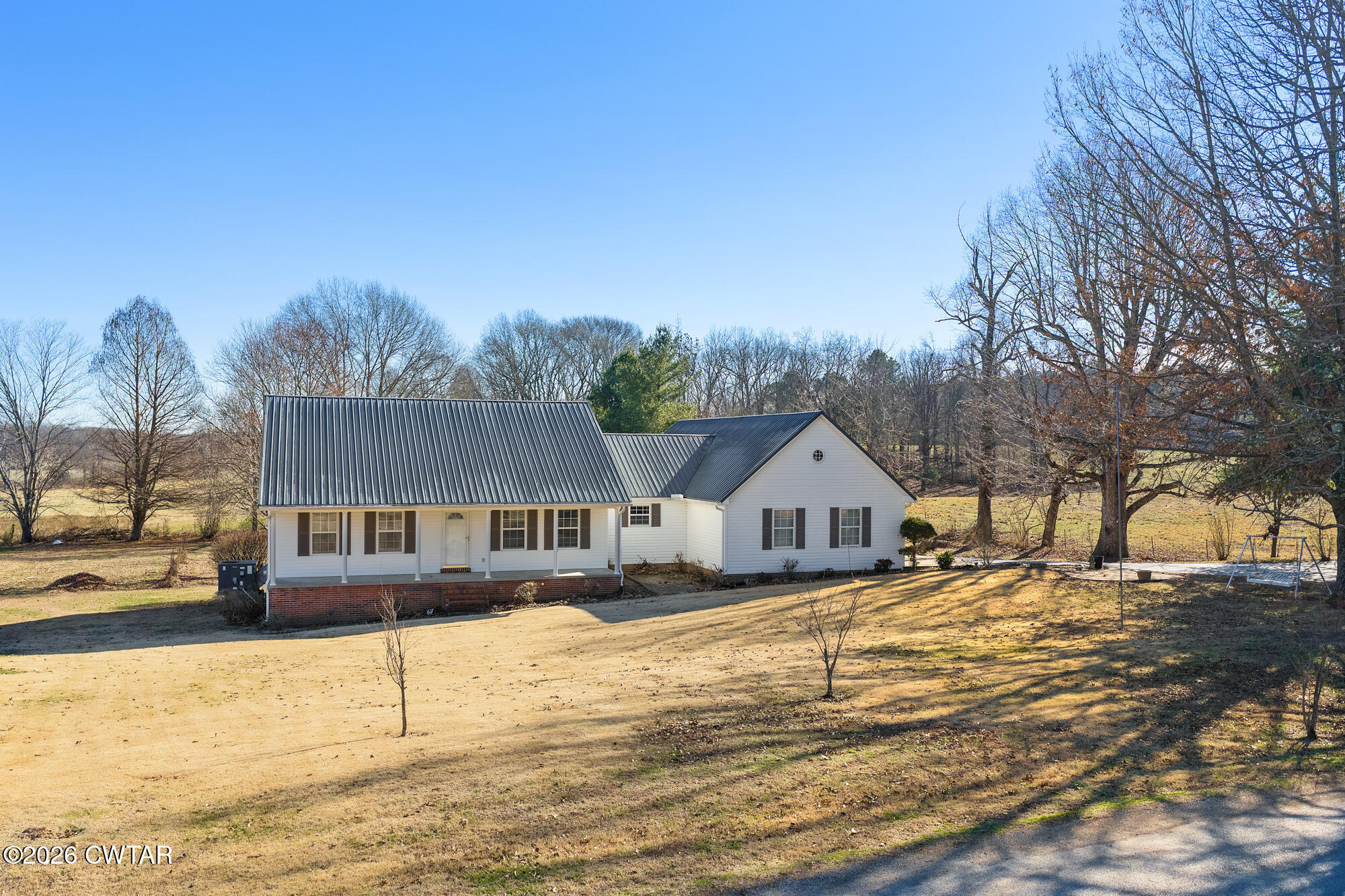 a front view of a house with a yard covered with snow and trees