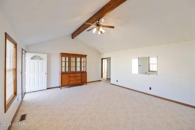 an empty room with chandelier fan and windows