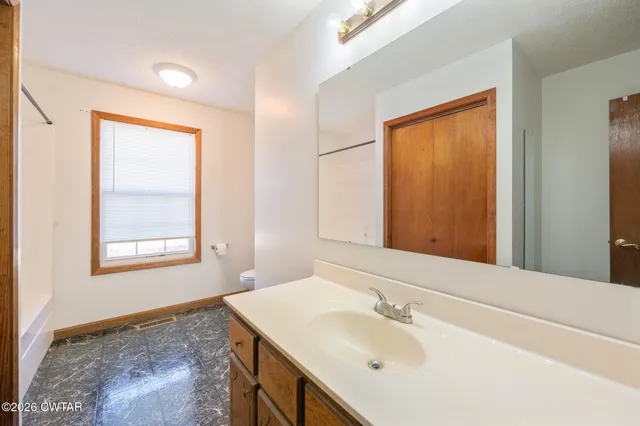 an empty room with windows and ceiling fan