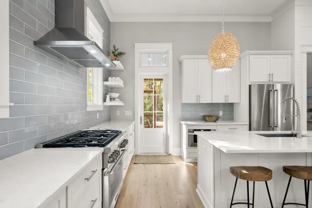 a kitchen with stainless steel appliances a stove a sink dishwasher and white cabinets with wooden floor