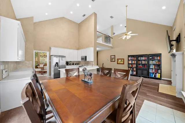 a dining room with stainless steel appliances a table chairs and a book shelf