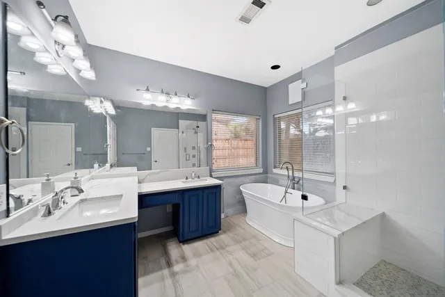 a bathroom with a double vanity sink mirror and bathtub