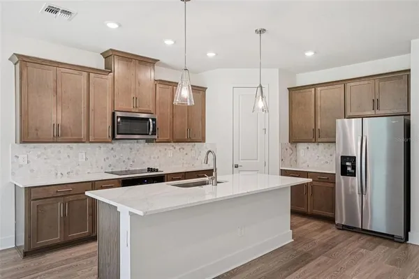 a kitchen with kitchen island a counter space a sink appliances and cabinets
