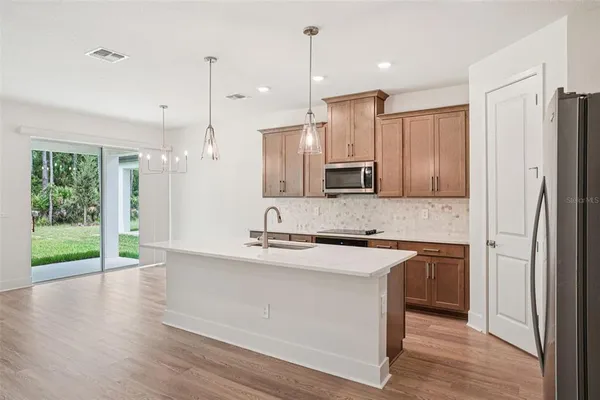 a kitchen with kitchen island granite countertop a sink a counter space appliances and cabinets