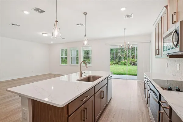 a kitchen with stainless steel appliances granite countertop a sink a stove and a wooden floors