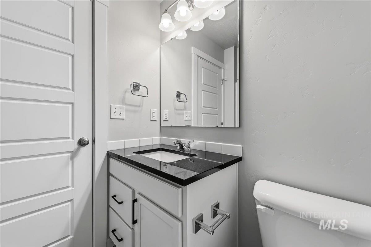 3091 S Green Boise, ID 83709 - Photo 19 of 27 Vanity with black countertop, white undermount sink, and chrome fixtures