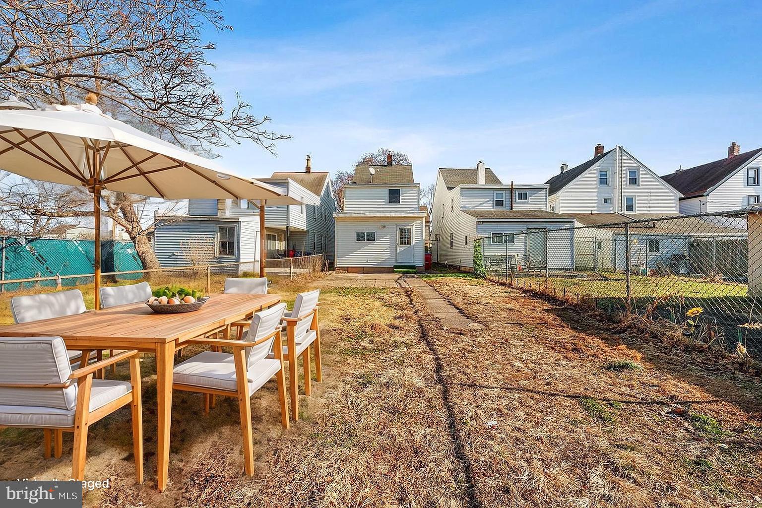 578 Swain Street Bristol, PA 19007 - Photo 15 of 17 a view of a white house with a table and chairs under an umbrella