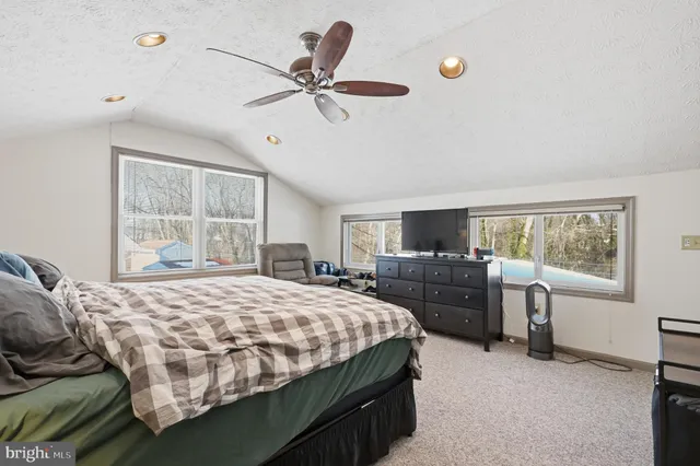 a bedroom with a large bed and a flat tv screen on dresser