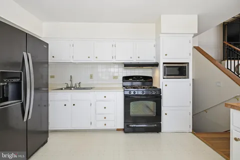 a kitchen with stainless steel appliances granite countertop a refrigerator a stove and white cabinets