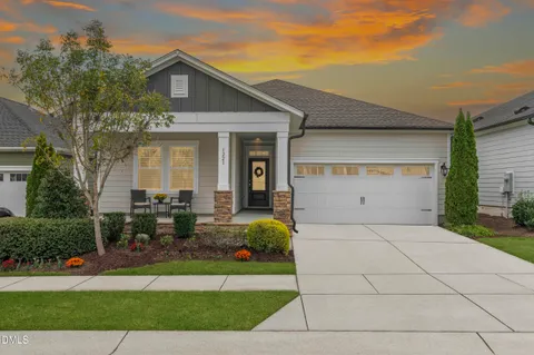 a view of a white house with a large windows and a yard with plants