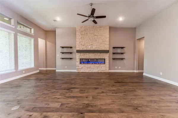 a view of a big room with wooden floor a ceiling fan and windows