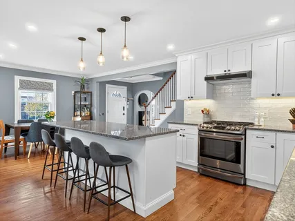 a kitchen with stainless steel appliances granite countertop a stove top oven a sink a dining table and chairs with wooden floor