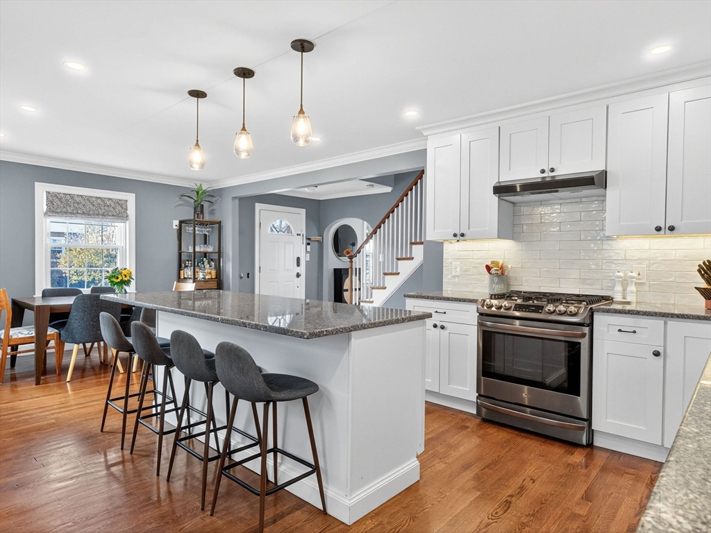 37 Rangeley Street Boston, MA 02124 - Photo 5 of 26 a kitchen with stainless steel appliances granite countertop a stove top oven a sink a dining table and chairs with wooden floor