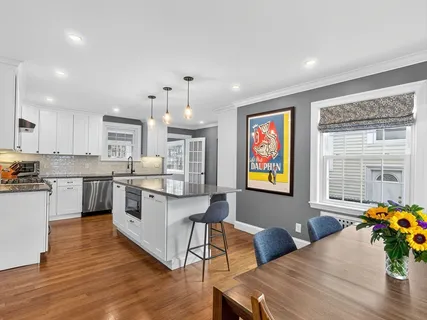 a kitchen with stainless steel appliances wooden floor dining table and chairs